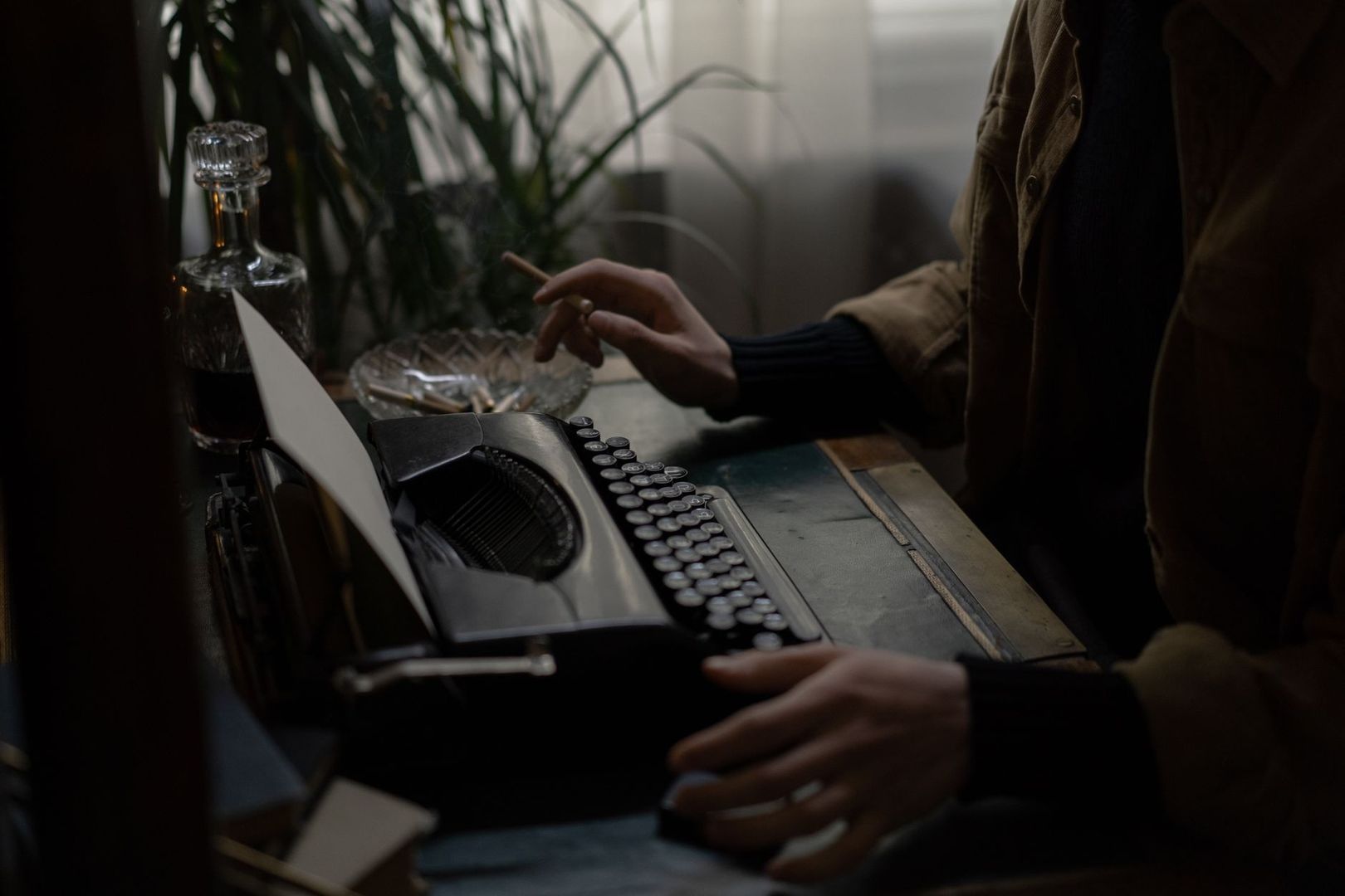 Writer smoking beside a vintage typewriter in a dim room